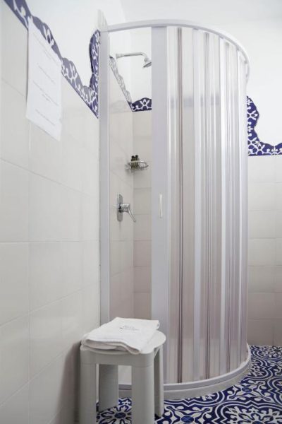 Baño con ducha de cabina semicircular y azulejos decorativos azules en Hotel La Terrazza