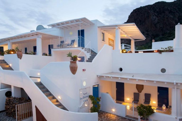 Fachada exterior blanca con terrazas iluminadas del Hotel La Terrazza al atardecer