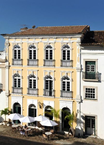 Fachada colonial amarilla del Hotel Villa Bahia en Salvador de Bahía con terraza y sombrillas