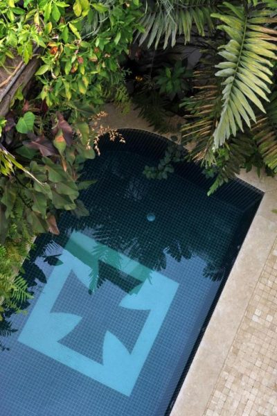 Piscina privada con mosaico azul rodeada de vegetación tropical en Hotel Villa Bahia