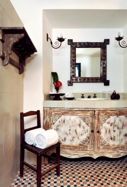Baño rústico con mueble vintage tallado y espejo artesanal en Hotel Villa Bahia