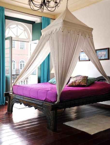 Habitación colonial con cama con dosel blanco y sábanas fucsia en Hotel Villa Bahia