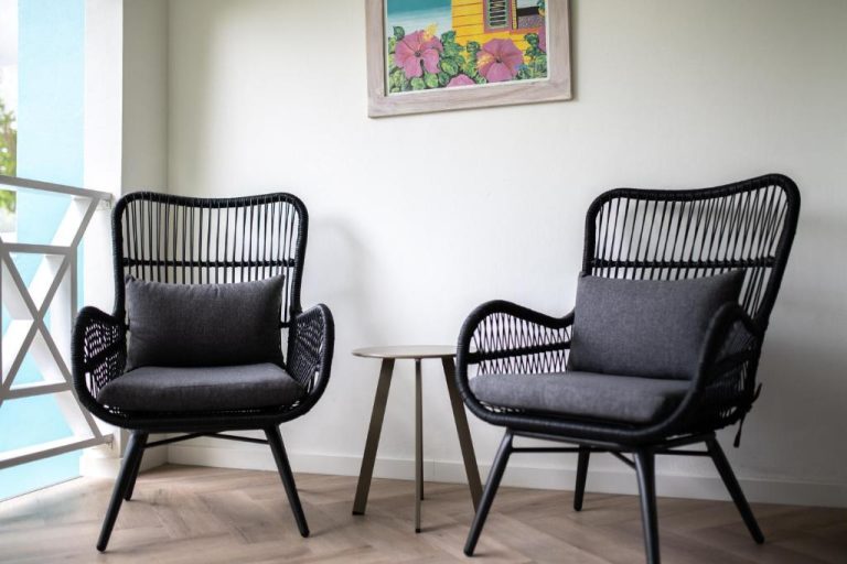 Dos sillones negros de ratán con cojines grises en la sala de estar de Blue Bay Lodges