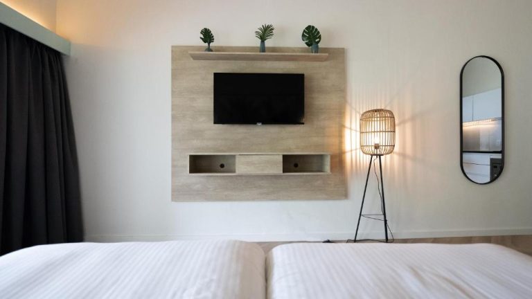 Habitación doble moderna con televisión empotrada y lámpara de ratán en Blue Bay Lodges
