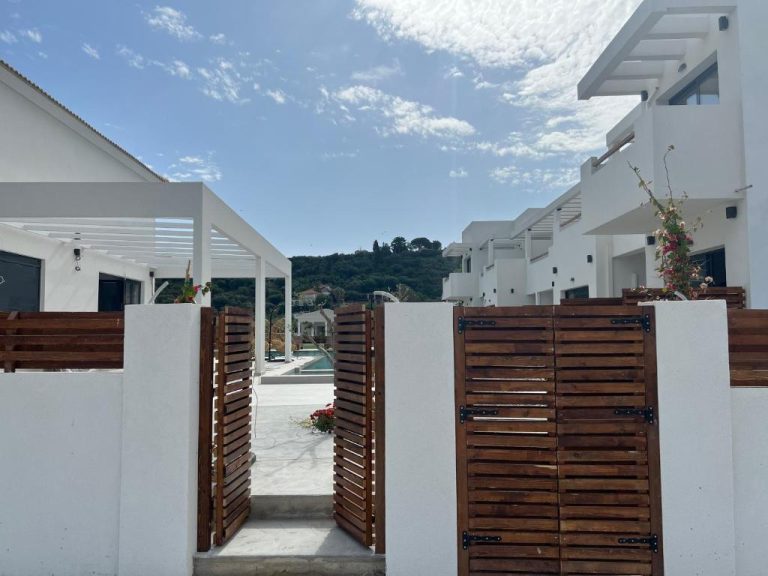 Entrada principal con puerta de madera y edificios blancos del Kimiro Hotel Tsilivi en Zakynthos
