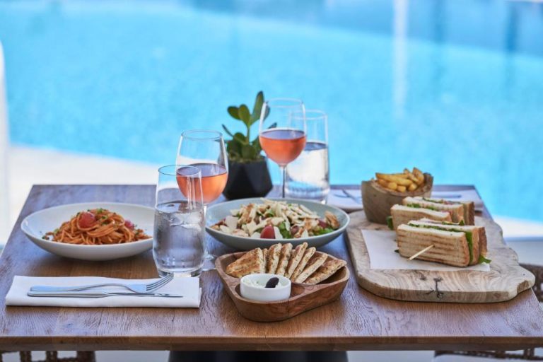 Mesa con pasta, sándwiches y vino rosado junto a la piscina del Paradise View Hotel