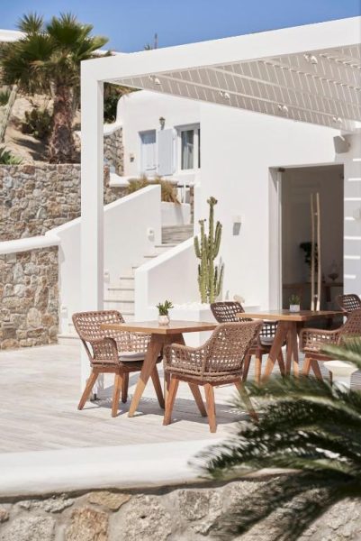Terraza exterior con mesa y sillas de ratán del Paradise View Hotel en Mykonos con vistas a arquitectura cicládica