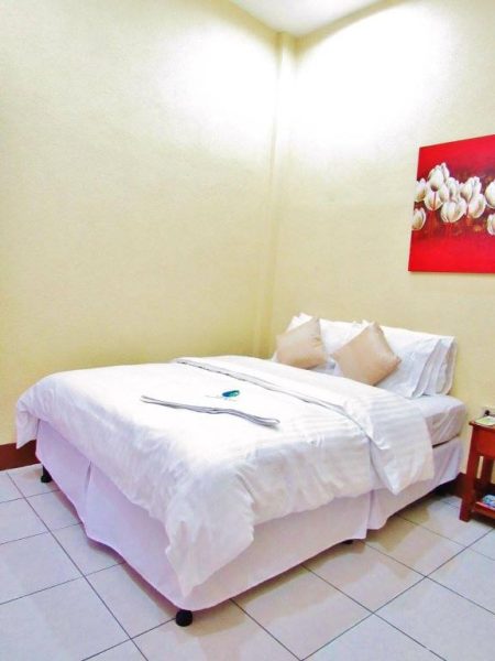 Habitación doble con cama matrimonial y ropa de cama blanca en Hotel Palmeras de Elim