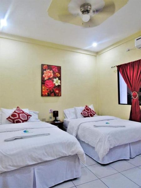 Habitación twin con dos camas dobles y decoración floral en Hotel Palmeras de Elim