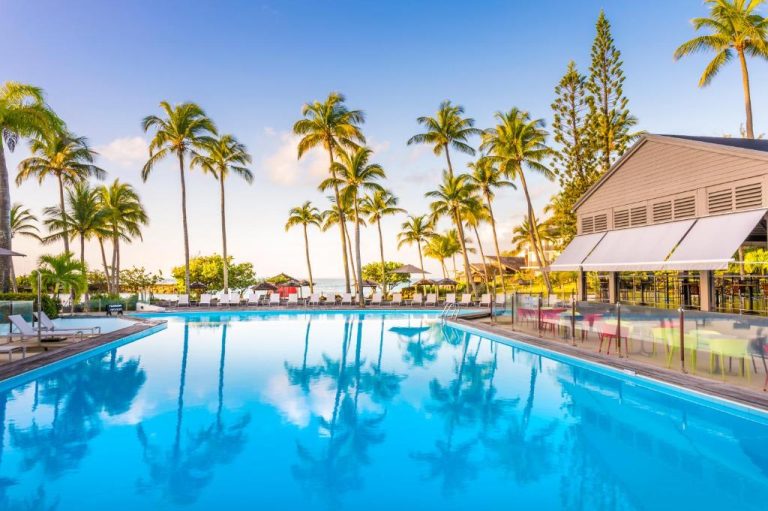 Piscina exterior con palmeras tropicales y terraza del Mahogany Hotel Residence & Spa