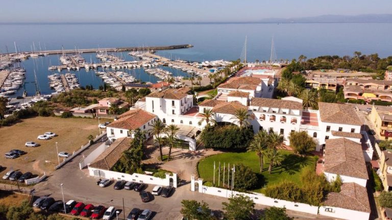Vista aérea del Phi Hotel Sighientu con puerto deportivo y marina llena de veleros en Cerdeña