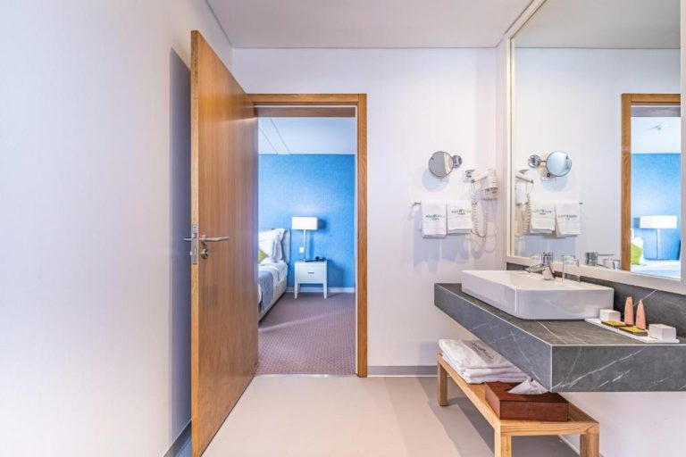 Baño moderno con lavabo de mármol y acceso a habitación azul en Aqua Natura Madeira