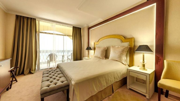 Habitación doble de lujo con cama king size y cabecero dorado en Imperial Palace Hotel