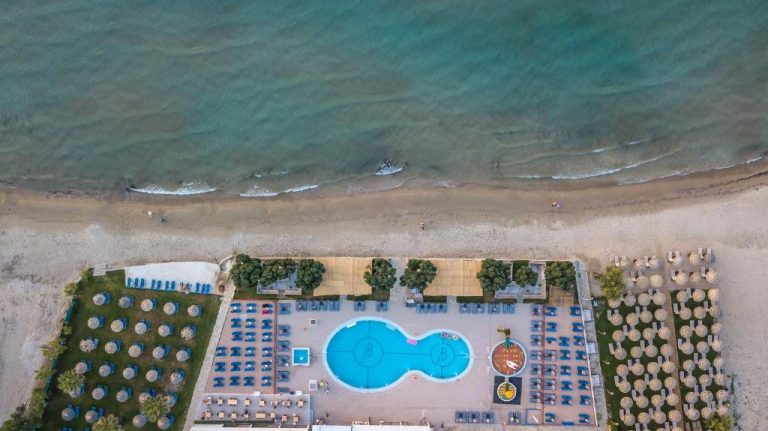 Vista aérea de la piscina exterior y zona de hamacas del Alykanas Beach Grand Hotel frente al mar en Zakynthos