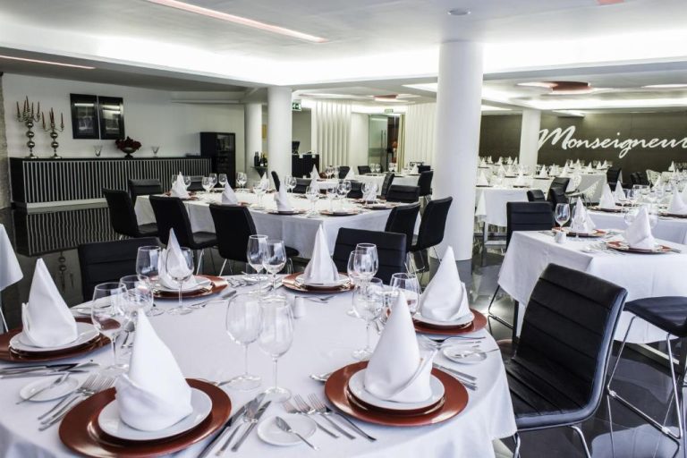 Salón de banquetes con mesas redondas elegantemente decoradas en el restaurante Monseigneur del Hotel Vip Praia