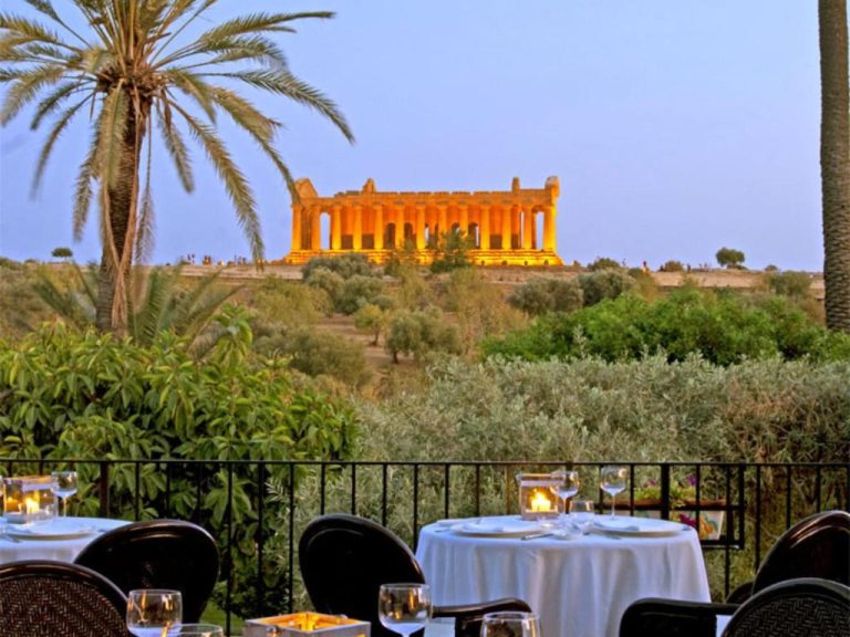 Terraza restaurante del Villa Athena Resort con vistas al iluminado Templo de la Concordia en Agrigento