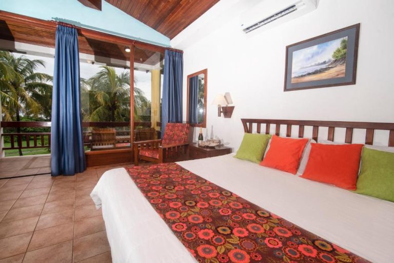 Habitación doble con terraza y vistas a palmeras en Nandel Beach Resort, cama king con cojines de colores