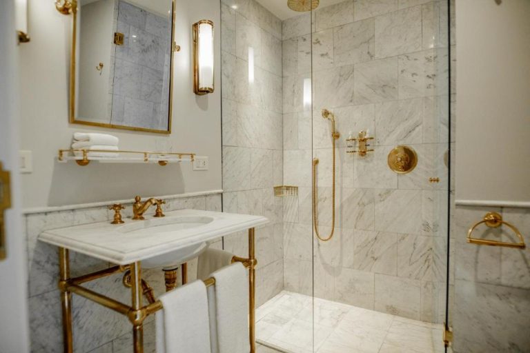 Baño de lujo con mármol blanco y accesorios dorados en el Hotel Montevideo Leading Hotels of the World