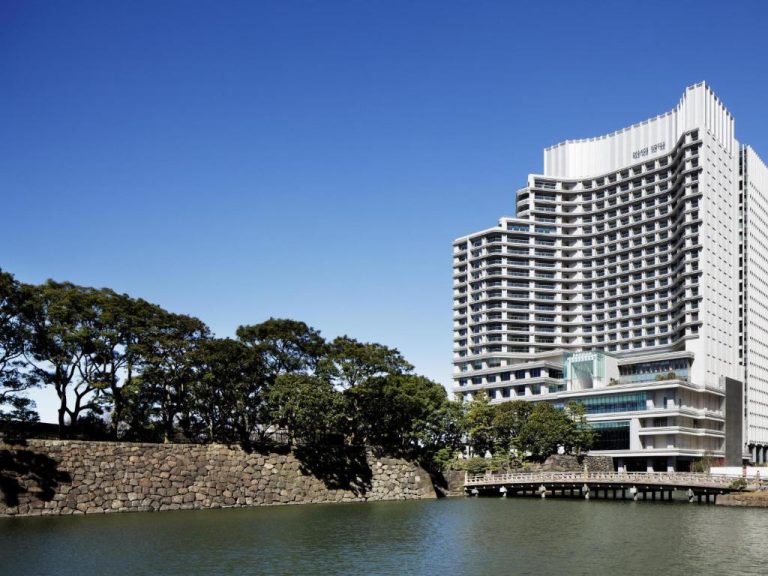 Vista exterior del Palace Hotel Tokyo junto al foso del Palacio Imperial con cielo azul