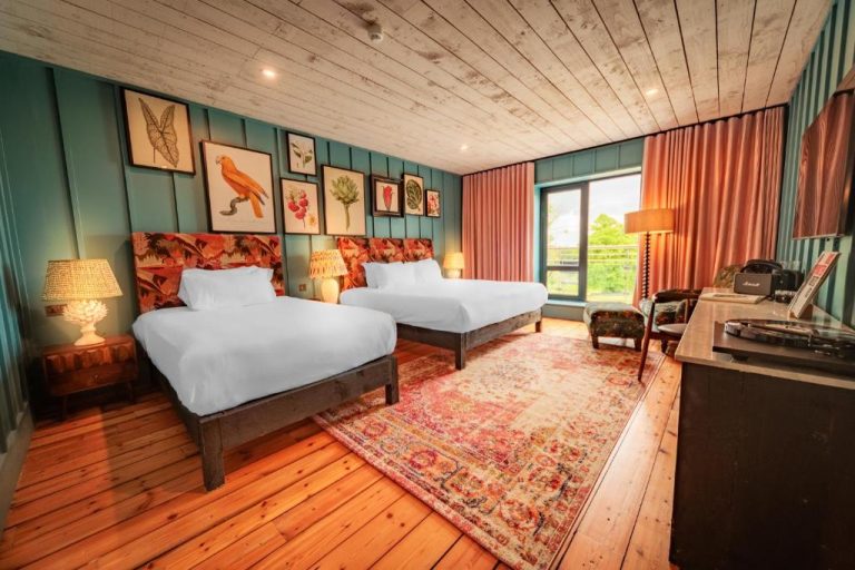 Habitación doble con suelo de madera y decoración botánica colorida en Glasson Lakehouse