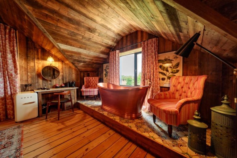Suite rústica con bañera exenta de cobre y decoración de madera en Glasson Lakehouse