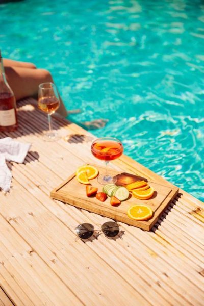 Tabla de frutas y cócteles junto a la piscina exterior del Glasson Lakehouse en un día soleado