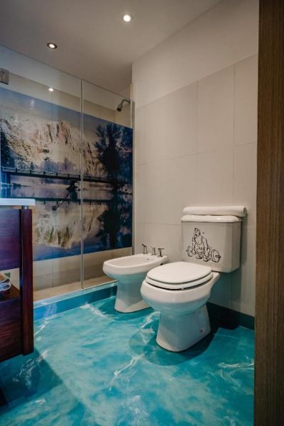 Baño moderno con suelo 3D efecto océano y ducha con mural en Shoshana Hotel Boutique