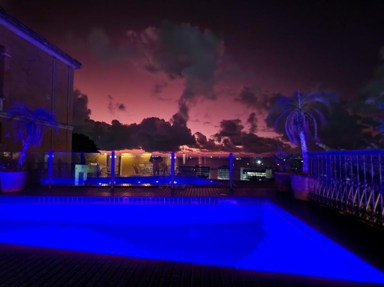 Piscina iluminada en azul del Hotel Casa do Amarelindo con vistas nocturnas de la ciudad al atardecer