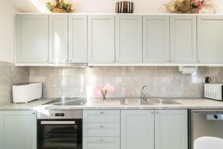 Cocina moderna equipada con armarios blancos y encimera de mármol en Kokkinos Studios With Pool & Sea View
