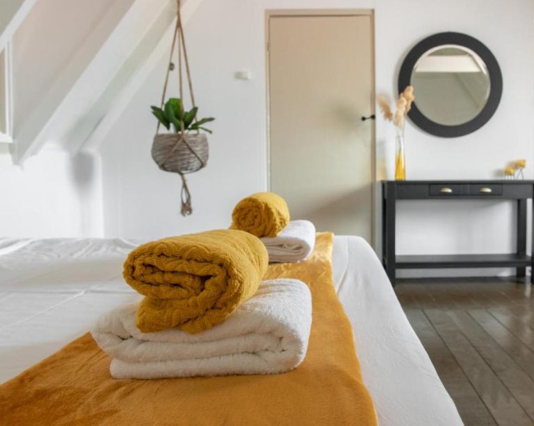 Habitación con cama doble y toallas mostaza del Landhuis Daniel Plantation House
