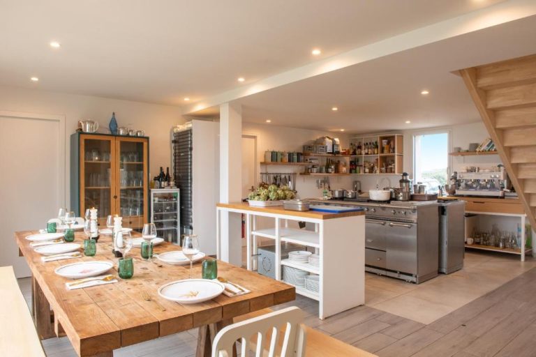 Comedor y cocina abierta con mesa de madera del Hôtel Sport & Spa Ile d'Ouessant, The Originals Collection