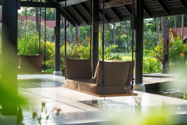 Columpio colgante con cojines sobre estanque en la zona lounge del Wyndham Hua Hin Pranburi Resort