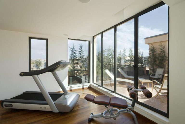 Gimnasio con cinta de correr y vistas a la terraza exterior en Palace Catania UNA Esperienze