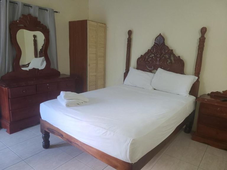 Habitación doble con cama de madera tallada y tocador con espejo en Tamboo Resort