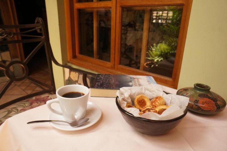 Taza de café negro con pastelería artesanal servida en mesa del Hotel Cafe con decoración colonial