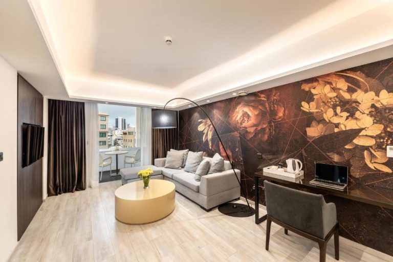 Salón de suite con sofá gris, escritorio y mural floral artístico en Almond Business Hotel
