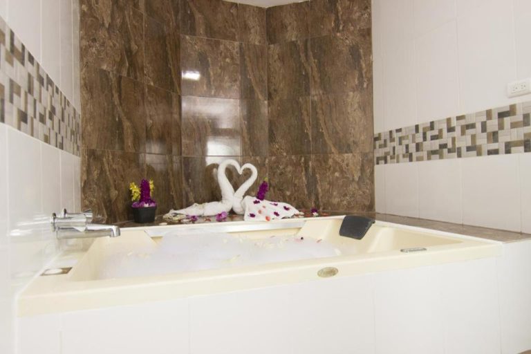 Jacuzzi romántico decorado con toallas en forma de cisnes y flores en el Hotel Gold Premium
