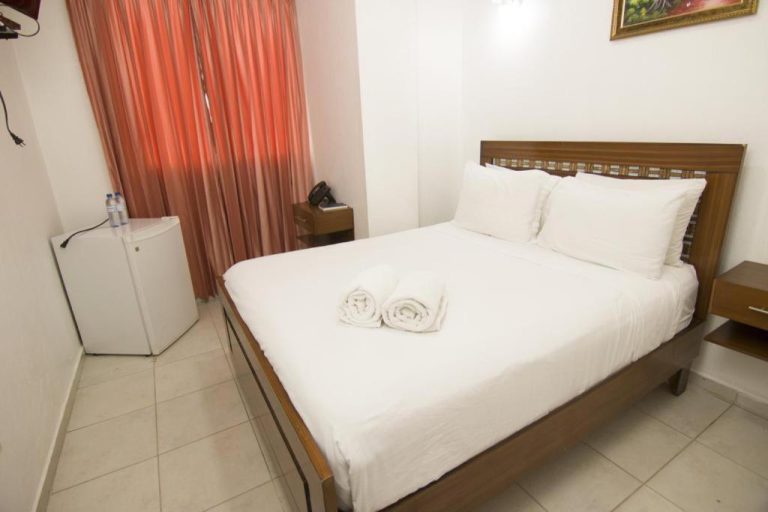 Habitación doble con cama matrimonial y ropa de cama blanca en Hotel Gold Premium