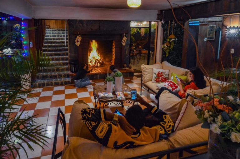 Sala con chimenea encendida y decoración navideña en Hotel Rancho Constanza & Cabañas de la Montaña