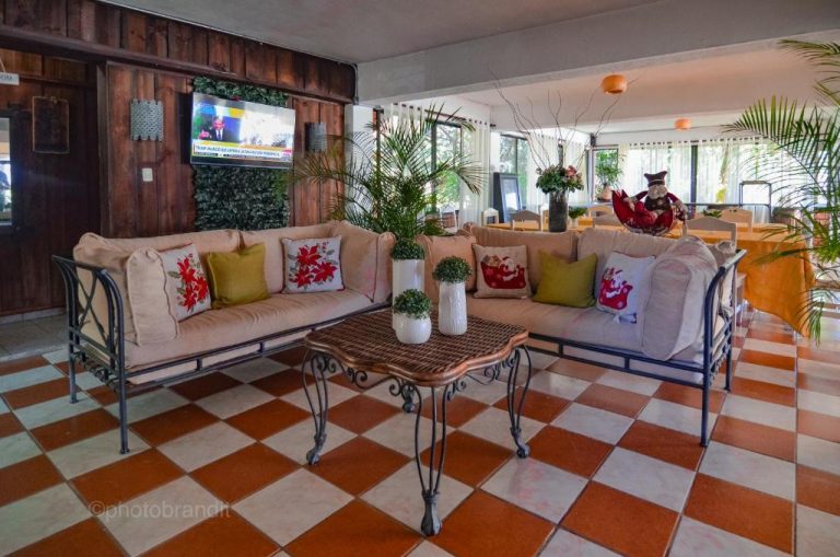 Sala de estar navideña con sofás y TV en el lobby del Hotel Rancho Constanza & Cabañas de la Montaña