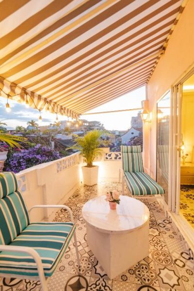 Terraza con toldo a rayas, tumbonas y mesa de mármol con vistas a la ciudad en Casa Hadasa