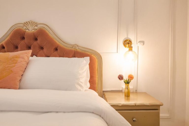 Habitación elegante con cabecero de terciopelo naranja y mesita de noche iluminada en Casa Hadasa