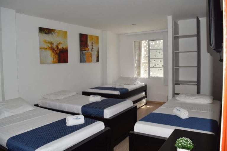 Habitación múltiple con cuatro camas individuales y decoración moderna en Hotel Travelers Sport