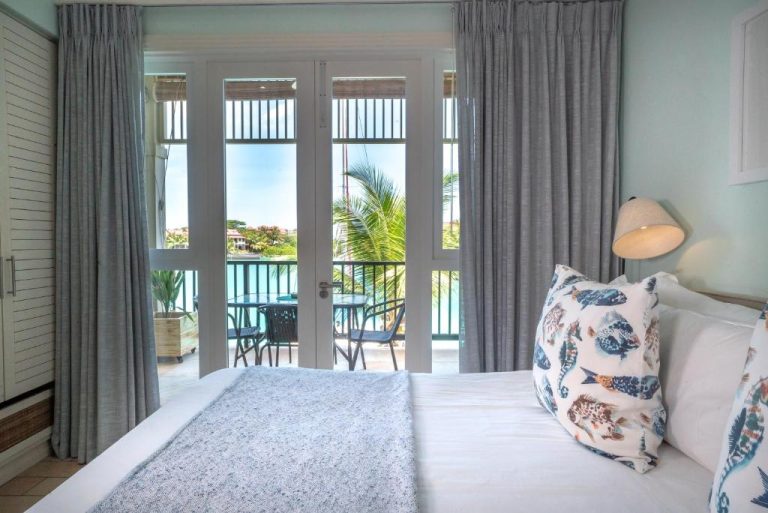 Habitación con cama doble y balcón con vistas al mar en Eden Island Self Catering Apartment