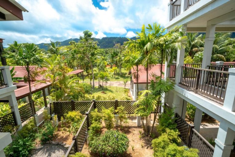 Jardín tropical con palmeras y vistas a la montaña en Eden Island Self Catering Apartment, Seychelles
