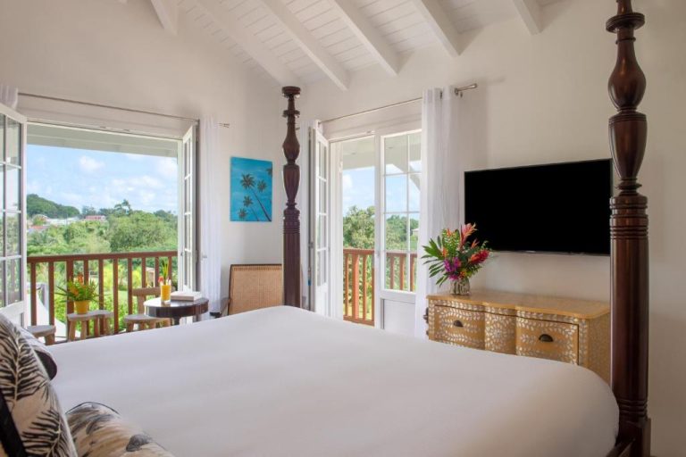 Habitación con cama de dosel y vistas al jardín tropical en Habitation Saint Charles Hôtel de Charme & Spa