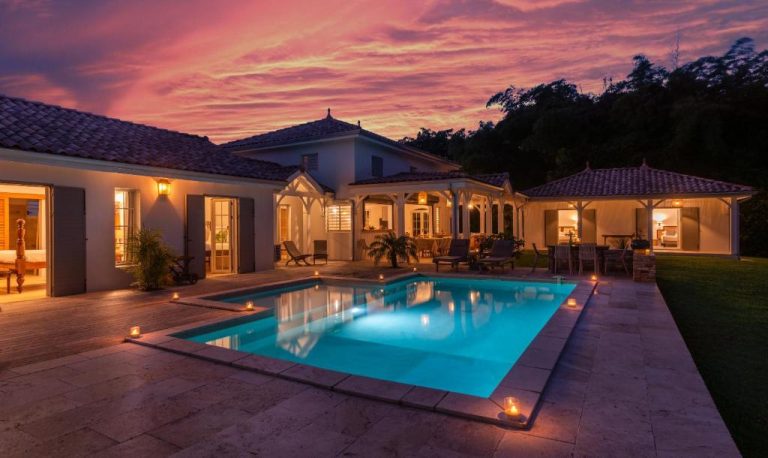 Piscina iluminada al atardecer con velas en Habitation Saint Charles Hôtel de Charme & Spa