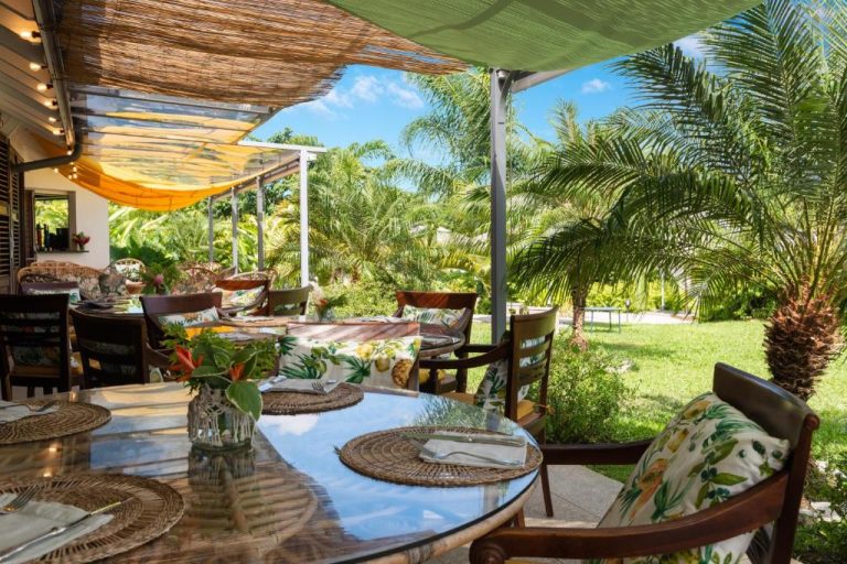 Terraza comedor al aire libre rodeada de jardín tropical en Habitation Saint Charles Hôtel de Charme & Spa