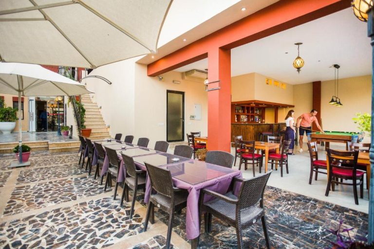 Terraza exterior con mesas y bar interior del Grand Hotel Madaba con mesa de billar al fondo
