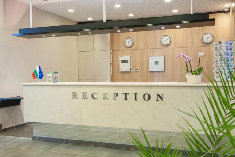 Recepción moderna del Park Hotel Kyustendil con mostrador de mármol y relojes mundiales en la pared